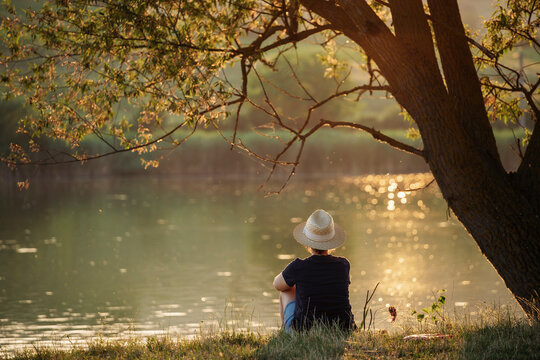 Woman enjoying solitude by the lake in warm summer sunset.