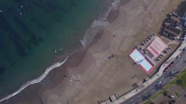 Aerial view of Circuito de Playas with sandy beach, surfboards, and coastal road in Chorrillos, Provincia de Lima, Peru.