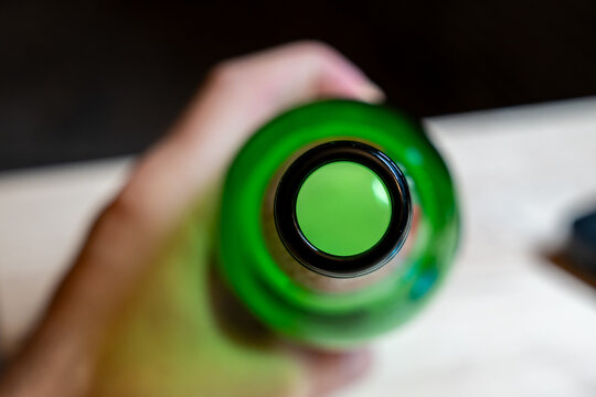 Green glass bottle bottom viewed from below, close-up overhead perspective showing circular rim and concave base, concept of glass material and packaging design