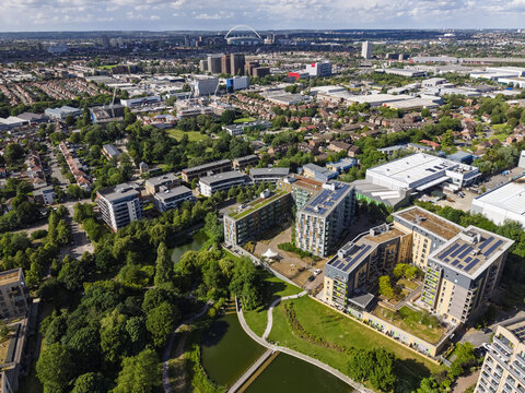 Aerial view of modern apartment buildings with green roofs and solar panels situated near a lake and parkland in the Park Royal area of London, England, United Kingdom.