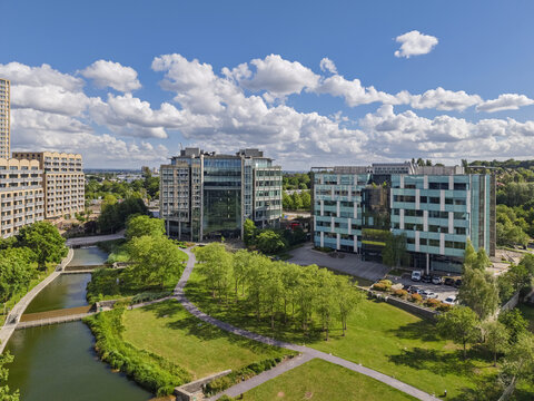 Aerial view of modern office buildings situated along a canal with lush green parkland and pathways in London, England, United Kingdom.