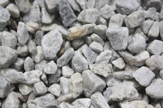 A top-down texture shot showing light gray, angular crushed stones or gravel.