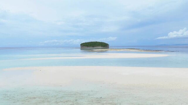 Aerial view of the pristine Pasir Timbul Mansuar sandbar surrounded by turquoise waters and a small lush island in Raja Ampat, Papua Barat Daya, Indonesia.