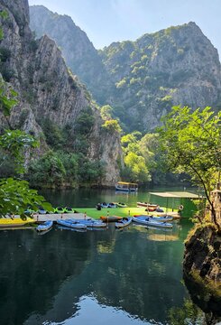 View of kayaks moored at a floating dock in the calm waters of Matka Canyon, surrounded by steep rocky cliffs and lush greenery in Skopje, Greater Skopje, North Macedonia.