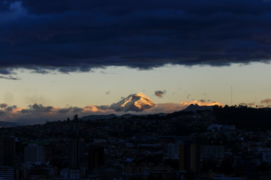 Dramatic Sky with Dark Clouds Frames Majestic Cotopaxi Volcano at Sunset Captured from Quito City