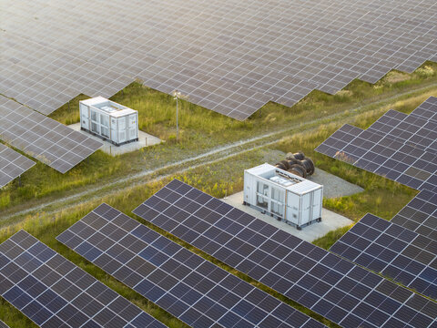 Aerial view of a large solar farm with rows of photovoltaic panels and electrical transformer units in a rural landscape in Rzezawa, Lesser Poland Voivode, Poland.