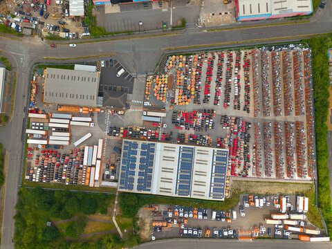 Aerial view of Eland Cables industrial site featuring large warehouses with solar panels, rows of cable drums, and parked trucks in Denaby Main, England, United Kingdom.