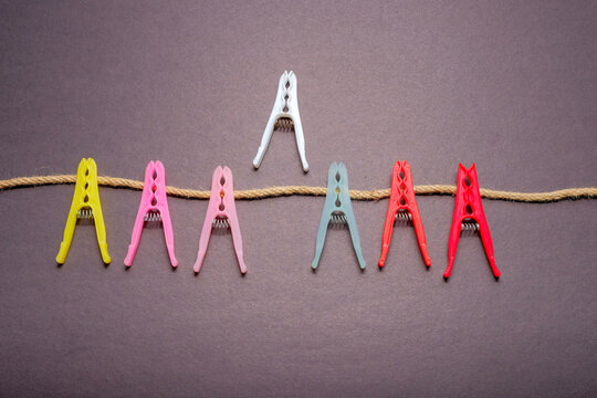 White clothespin standing above colorful pegs line on clothesline