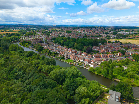 Aerial view of the river winding through lush green trees and residential houses in Mexborough, England, United Kingdom.