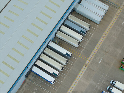 Aerial view of an industrial distribution centre with multiple semi-trailers parked at loading bays in a concrete yard in Doncaster, England, United Kingdom.