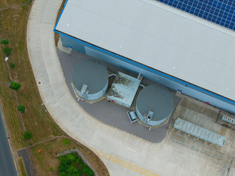 Aerial view of industrial storage tanks and a large warehouse facility with solar panels on the roof, situated next to a concrete service road in Doncaster, England, United Kingdom.