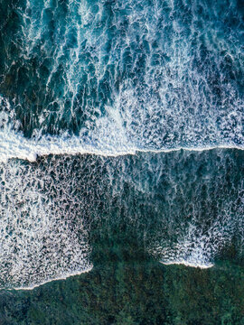 Aerial view of ocean waves crashing over a coral reef in the turquoise waters of Mauritius.