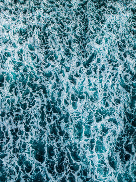 Aerial view of turquoise ocean waves with white sea foam patterns in Mauritius.