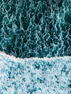 Aerial view of deep blue ocean waves with white sea foam crashing against the surface in Mauritius.