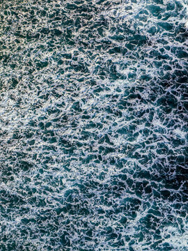 Aerial view of deep blue ocean water with intricate white sea foam patterns creating a textured surface near the coast of Mauritius.