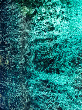 Aerial view of a vibrant coral reef with intricate textures and varying shades of turquoise and deep blue water in Mauritius.