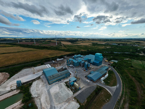 Aerial view of Saint Gobain Formula industrial plasters and gypsum manufacturing facility surrounded by fields and wind turbines in New Balderton, England, United Kingdom.