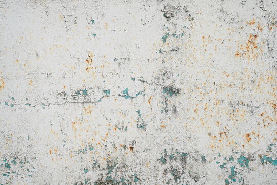 White rusty metal texture background with peeling paint closeup. Weathered corroded iron surface with flaking turquoise blue paint under white layer and subtle rust spots.