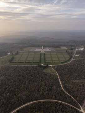 Aerial view of the Douaumont Ossuary and its vast military cemetery surrounded by dense forest in the Grand Est region, Douaumont-Vaux, Grand Est, France.