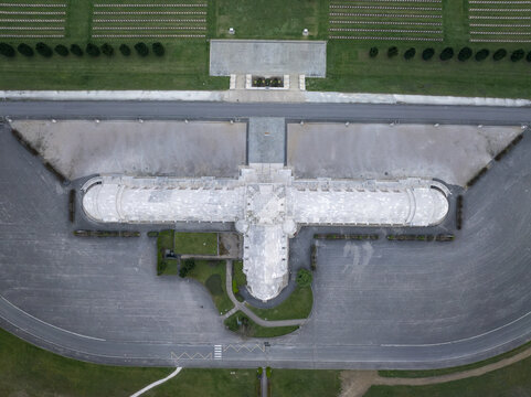 Aerial view of the Douaumont Ossuary, a historic memorial building surrounded by rows of white crosses in the military cemetery, with paved courtyards in Douaumont-Vaux, Grand Est, France.