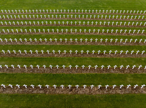 Aerial view of the Douaumont Ossuary military cemetery with rows of white crosses set in green grass in Douaumont-Vaux, Grand Est, France.