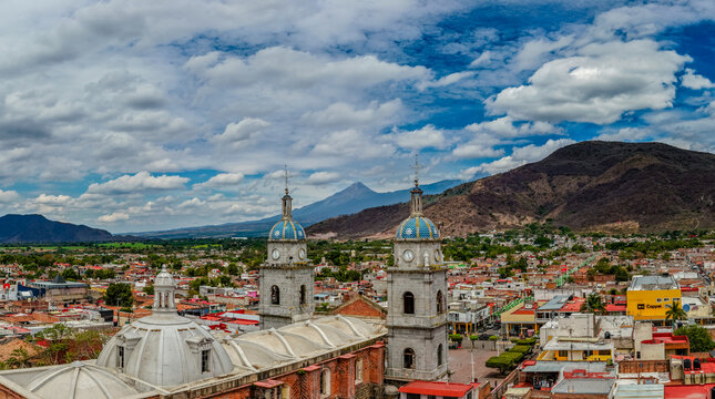 Tuxpan, Jalisco, Mexico - 30 May 2025: Aerial view of the Parroquia de San Juan Bautista with its distinctive blue-tiled domes, overlooking the town and mountains.