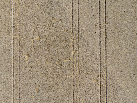 Aerial view of agricultural field with parallel tractor tracks across the soil in Hombourg, Grand Est, France.