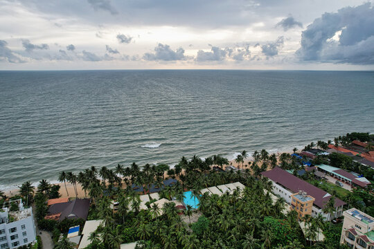 Aerial view of Long Beach with lush palm trees, resort buildings, a swimming pool, and sandy coastline along the ocean in Phu Quoc, Kien Giang, Vietnam.