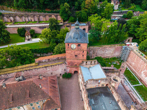 Aerial view of Heidelberg Castle, featuring its iconic red sandstone clock tower, historic courtyard, and surrounding lush green parkland in Heidelberg, Baden-Wurttemberg, Germany.
