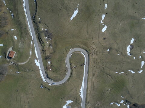 Aerial view of the winding road on the slopes of Monte Nerone with patches of snow in Apecchio, Marche, Italy.
