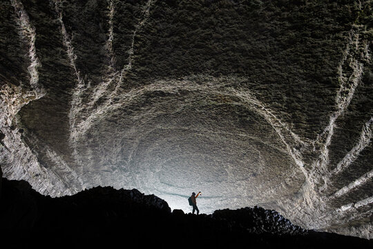 View of a lone explorer standing inside the massive, textured cavern of Zhijin County in Bijie, Guizhou, China.