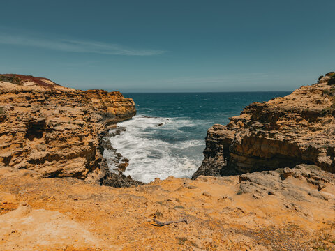 View of the rugged sandstone cliffs and crashing waves along the Great Ocean Road in Lorne, Victoria, Australia.