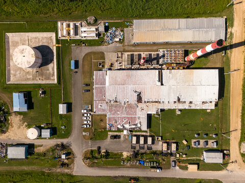 Aerial view of Tinian power station with its red and white striped smokestack, industrial buildings, storage tanks, and grassy grounds San Jose, Tinian, Northern Mariana Islands.