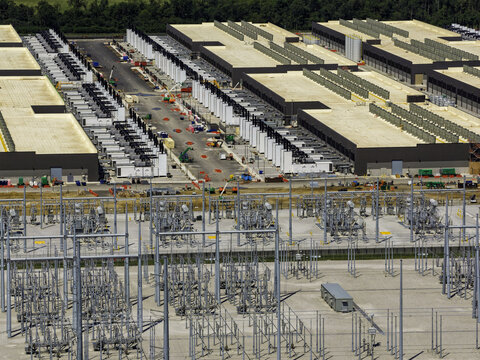 Aerial view of a large data center facility featuring long industrial buildings, rows of cooling units, and an expansive electrical substation in New Carlisle, Indiana, United States.