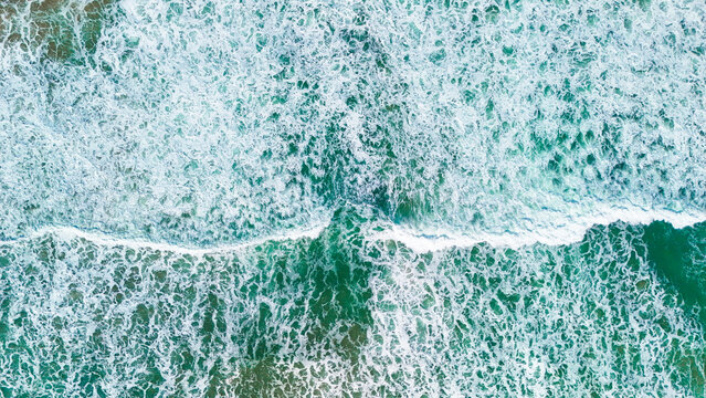 Aerial view of ocean waves crashing on a beach in Indonesia.