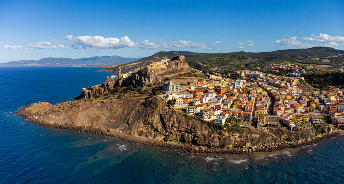 Aerial view of the historic town of Castelsardo perched on a rocky cliff overlooking the Mediterranean Sea with colorful houses and the Doria Castle.