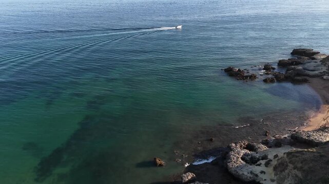 serene coastal ocean landscape with rocks from aerial view in travel and nature context. blue and green hues dominate the tranquil scene. water and rocks create a natural setting.