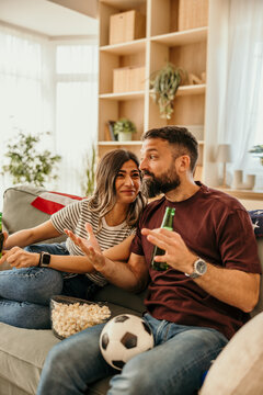 Couple watching football game at home discussing strategy