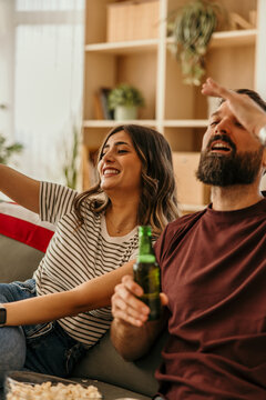 Happy couple cheering sport with beer and popcorn