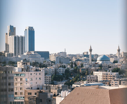View of the Amman skyline featuring modern skyscrapers and the blue dome of the King Abdullah I Mosque under a clear sky in Amman, Amman Governorate, Jordan.