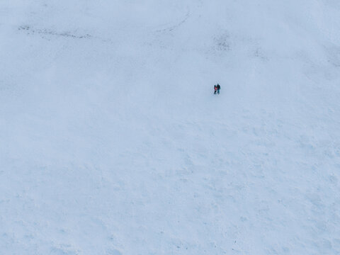 Mikoszewo, Pomeranian Voivodeship, Poland - 20 February 2026: Aerial view of two people walking across a vast, snow-covered landscape.