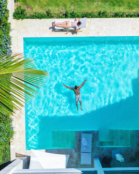 Aerial view of Senator Puerto Plata Hotel featuring a turquoise swimming pool with a man swimming and a woman relaxing on a lounge chair in Puerto Plata, Puerto Plata, Dominican Republic.