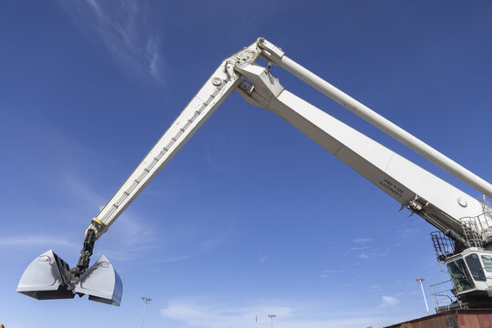 View of a large industrial crane arm with a grab bucket extended against a clear blue sky at Kilindini Harbour in Mombasa, Kwale County, Kenya.