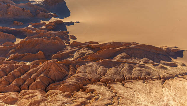 Aerial view of the rugged, arid landscape of the Valley of the Moon with unique rock formations, vast sand dunes, and deep shadows in San Pedro de Atacama, Antofagasta, Chile.