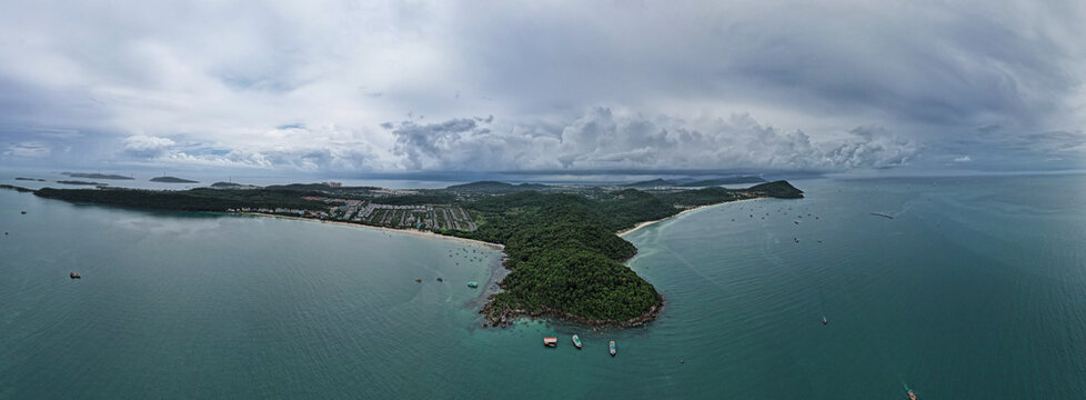 Aerial view of Khem Beach featuring luxury resorts, lush green hills, and small boats floating in the turquoise sea, Phu Quoc, An Giang, Vietnam.