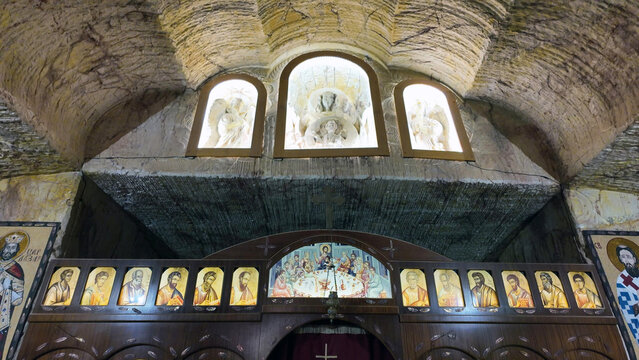 Coober Pedy, Australia - 15 January 2025: View of the interior of the underground Serbian Orthodox Church, featuring carved rock walls, a wooden iconostasis with icons, and illuminated alcoves.