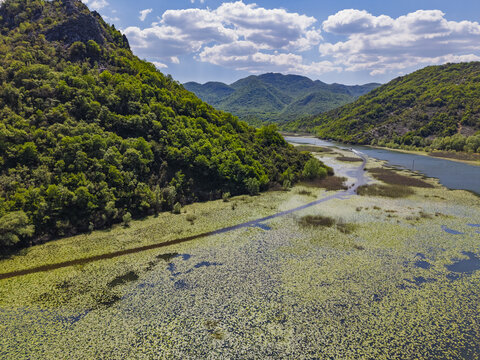 Aerial view of Pavlova Strana viewpoint overlooking the winding Rijeka Crnojevica river, lush green hills, and water lilies in Rijeka Crnojevica, Prijestonica Cetinje, Montenegro.
