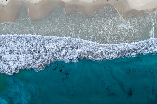 Aerial view of Cosy Corner Beach with turquoise ocean waves crashing onto the sandy shore in Albany, WA, Australia.