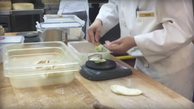 中華料理店の厨房でシェフが手作り餃子を仕込む調理風景
