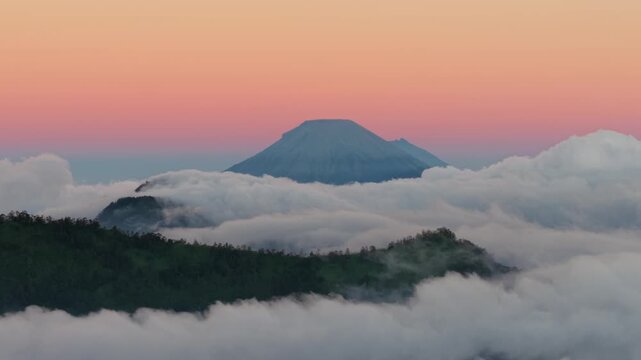 Aerial view of Dieng Plateau mountain peak rising above a sea of clouds at sunset in Kecamatan Batur, Jawa Tengah, Indonesia.